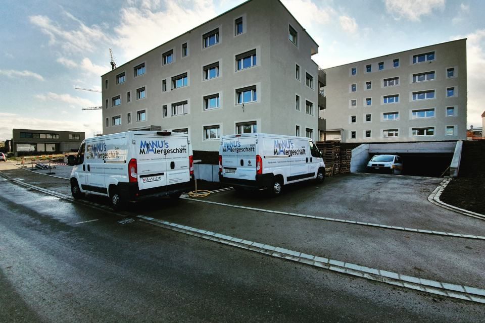 Fahrzeuge der Manu's Malergeschäft AG vor einem Wohngebäude